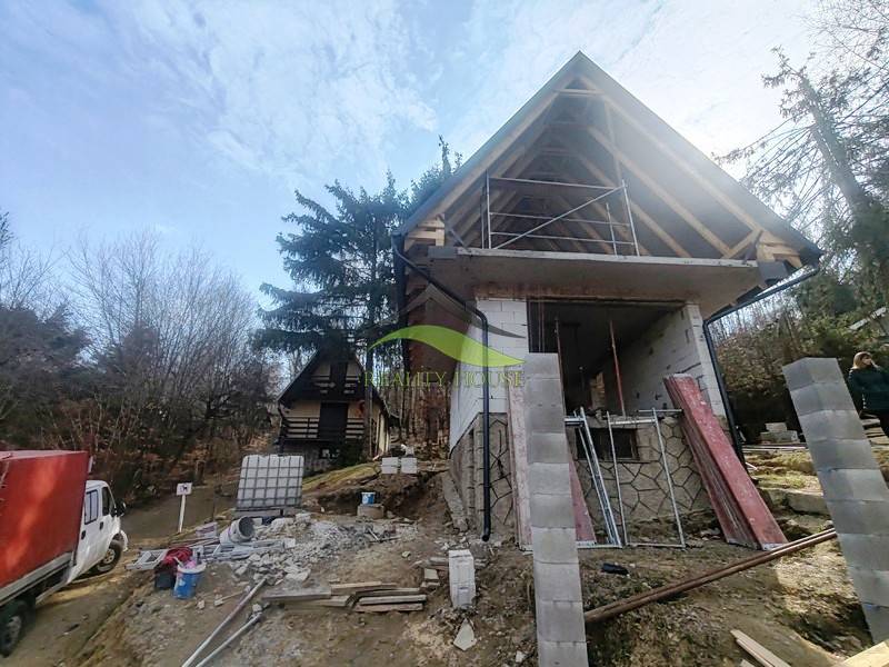 Eine Hütte im Bau auf Zajačia Debra in Holčíkovce, umgeben von Bäumen und Baumaterial.