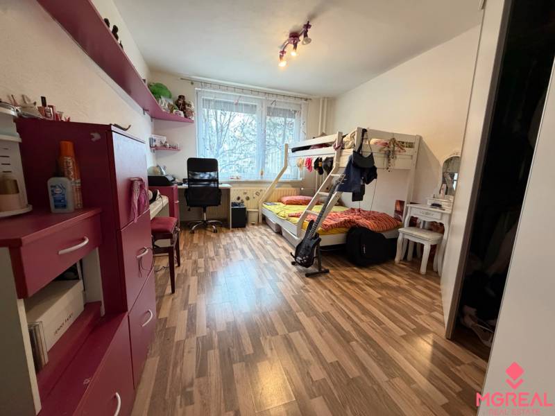 Kinderzimmer mit Schrank, Etagenbett und Boden mit Holzdekor in einer 3-Zimmer-Wohnung.