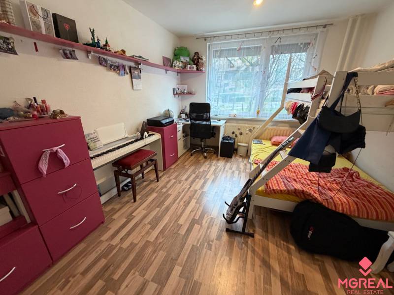 Ein Zimmer in einer 3-Zimmer-Wohnung mit einem Etagenbett, einem Schreibtisch und einem Boden in Holzoptik.