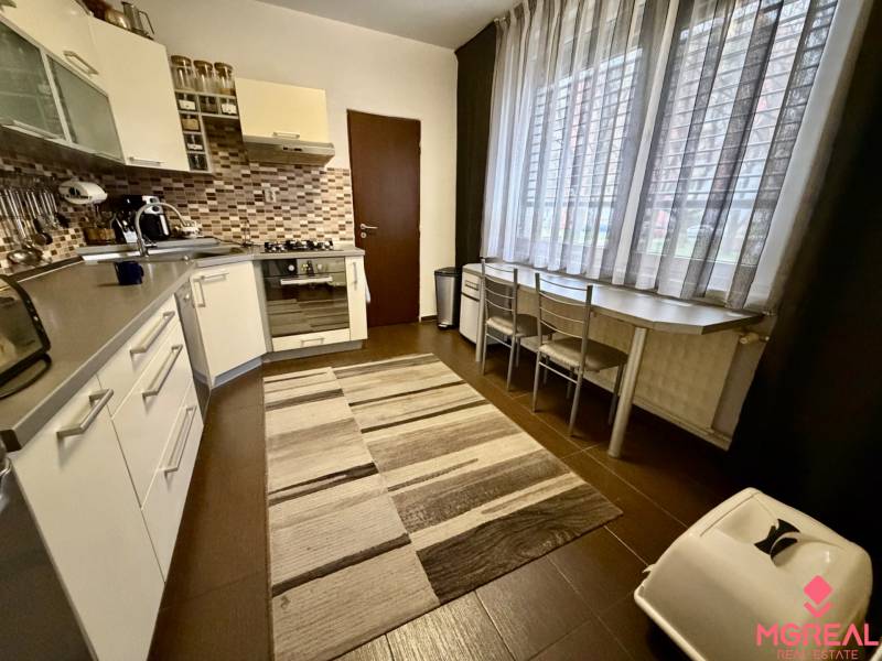 Küche in einer 3-Zimmer-Wohnung mit dunklem Boden und großem Fenster.