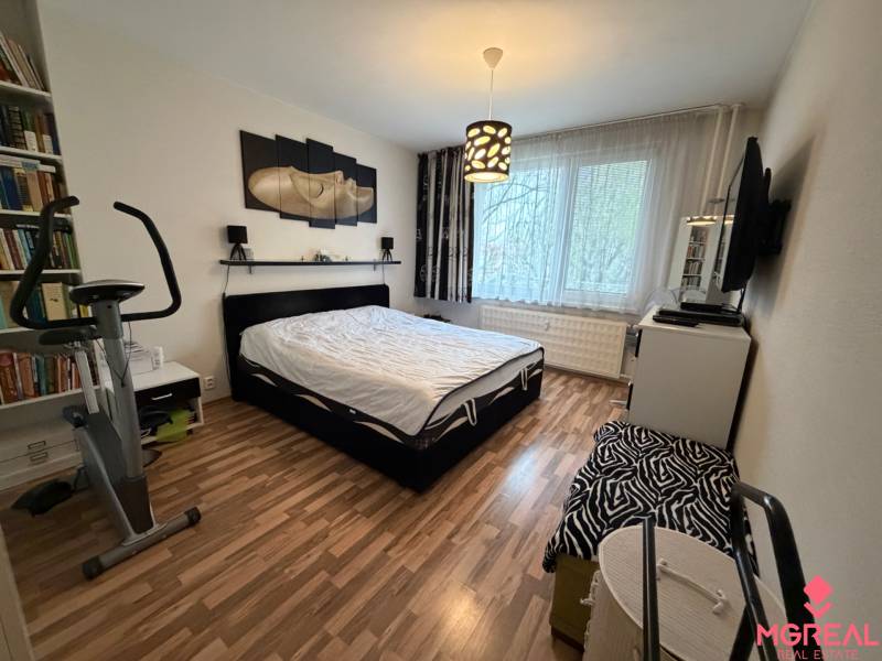 Schlafzimmer in einer 3-Zimmer-Wohnung mit Holzboden und einem Heimtrainer.