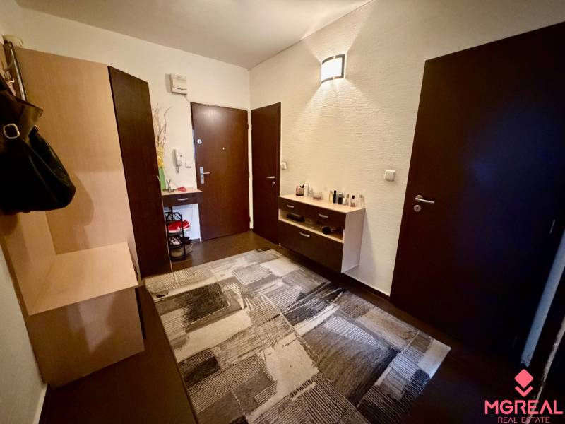 Eingangsbereich mit dunklen Türen, Kommode und Boden mit Holzdekor in einer 3-Zimmer-Wohnung.