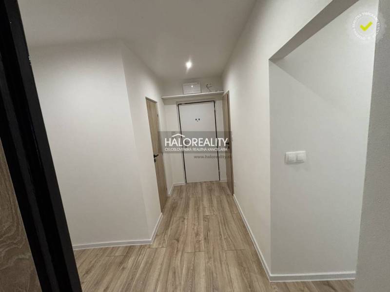 Flur in einer 3-Zimmer-Wohnung mit Holzboden und weißen Wänden.