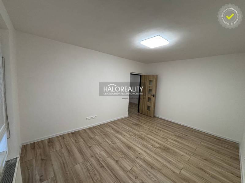 Ein geräumiges Zimmer in einer 3-Zimmer-Wohnung mit einem Boden in Holzoptik und weißen Wänden.