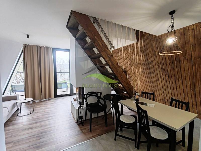 Eine Hütte mit einem Boden in Holzoptik, einer Treppe und einem Tisch neben einer Wand aus Holzlamellen.