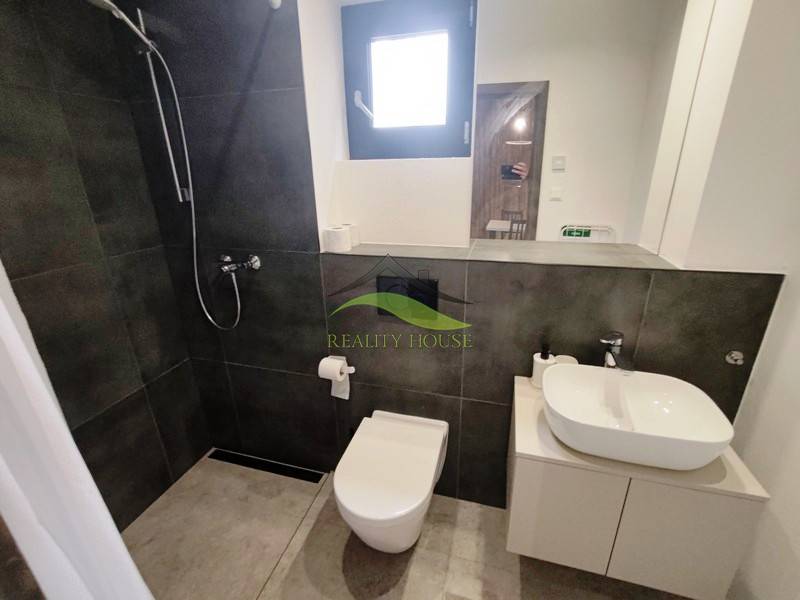 Ein Badezimmer in einer Hütte mit einer Duschkabine, einem modernen Waschbecken und einer Toilette auf einem Boden mit Holzdekor.