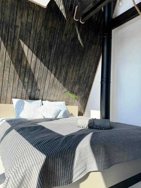 Bett mit gestreifter Decke und Holzwänden in der Hütte.