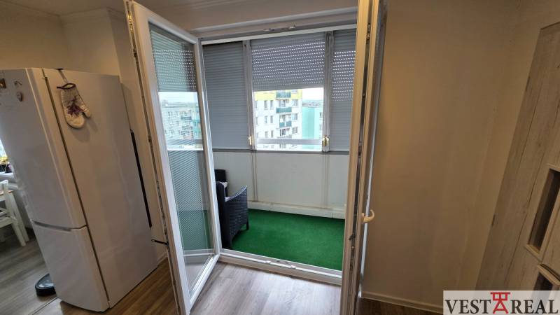 Der Balkon einer 3-Zimmer-Wohnung mit offenen Türen und Ausblick, Boden mit Holzdekor.