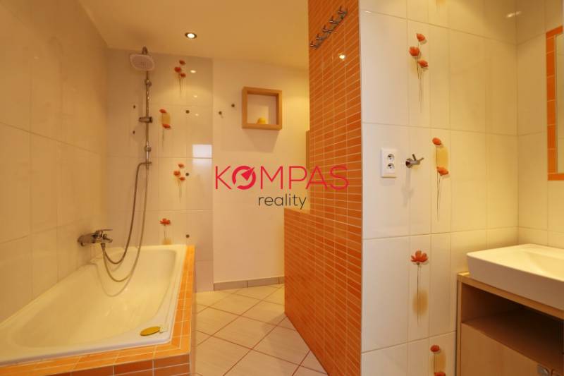 Badezimmer mit orangefarbenen Fliesen in einer 3-Zimmer-Wohnung, mit Waschbecken und Badewanne mit Kacheln.