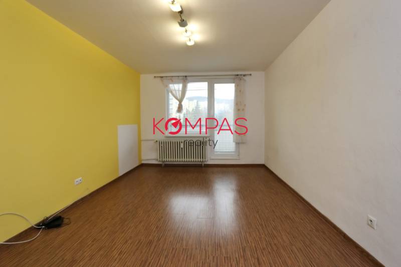 Ein Zimmer in einer 3-Zimmer-Wohnung mit einem Boden in Holzoptik und einer gelben Wand.