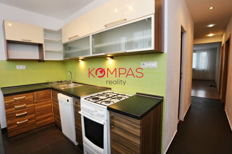 Küche in einer 3-Zimmer-Wohnung mit Holzboden und grüner Wandverkleidung.