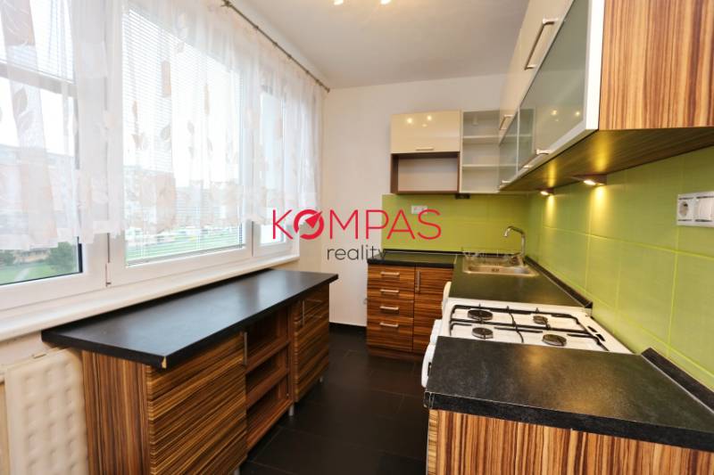 Küche in einer 3-Zimmer-Wohnung mit grünen Fliesen und einem Boden in Holzoptik.