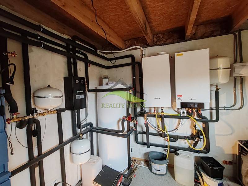 Technische Heizungsanlage in einem Einfamilienhaus mit verbundenen Rohren und Boiler.
