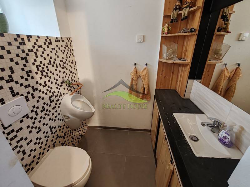 Badezimmer in einem Einfamilienhaus mit Waschbecken, Spiegel und Mosaikfliesen.