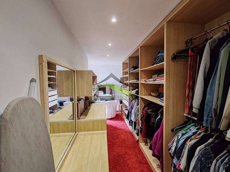 Ein Kleiderschrank in einem Einfamilienhaus mit rotem Teppich und eingebauten Regalen.