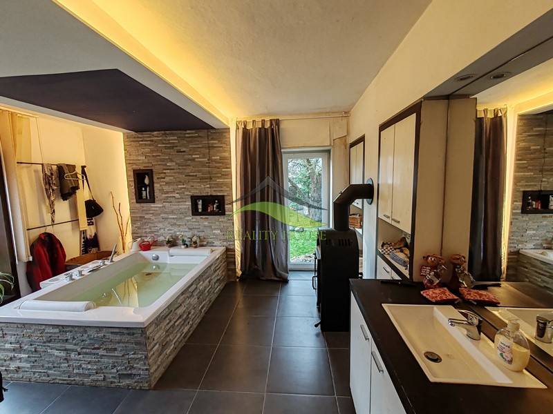 Geräumiges Badezimmer mit Badewanne und Fliesen in einem Einfamilienhaus, Boden mit Holzdekor.