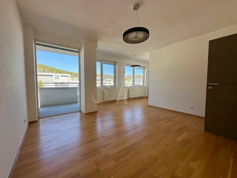 Wohnzimmer in einer 4-Zimmer-Wohnung mit Holzboden und Balkon.