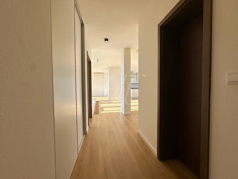 Der Flur in der 4-Zimmer-Wohnung mit einem Boden in Holzoptik und einem Einbauschrank.