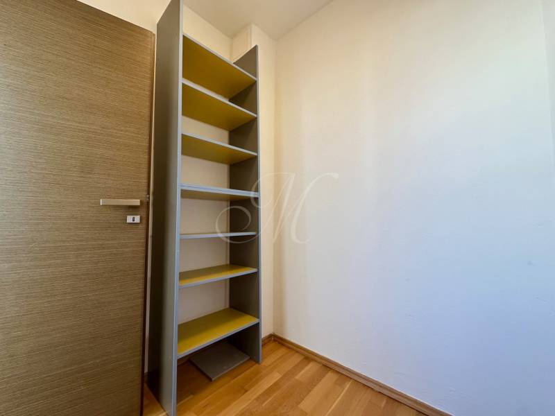 Ein Holzregal mit Regalböden in einem Raum mit einem Boden in Holzoptik, 4-Zimmer-Wohnung.