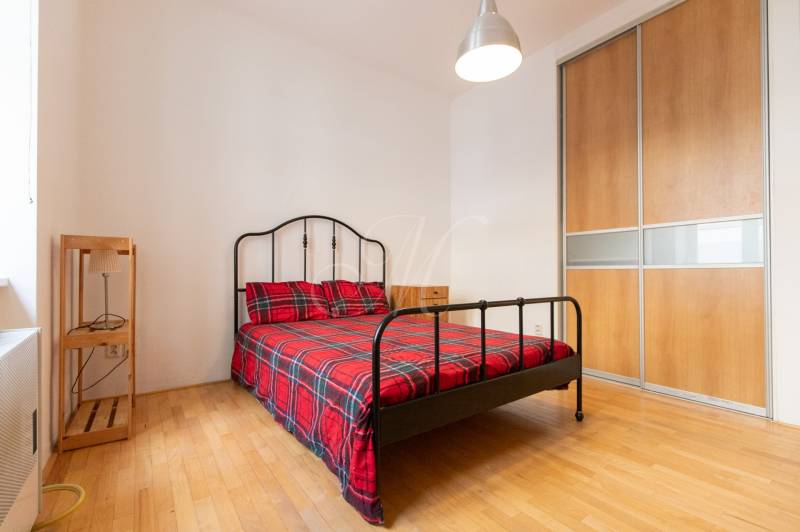Schlafzimmer in einer 4-Zimmer-Wohnung mit einem Metallbett, einem Kleiderschrank und einem Boden in Holzoptik.