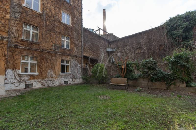 Der Hof des Wohnhauses in der Medená-Straße in Bratislava - Altstadt mit einer Bank und Grünflächen.
