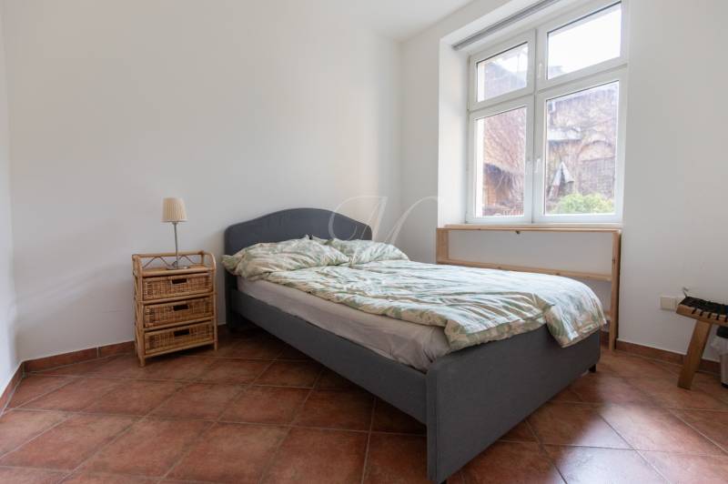 Schlafzimmer in einer 4-Zimmer-Wohnung mit Bett, Nachttisch und großem Fenster.