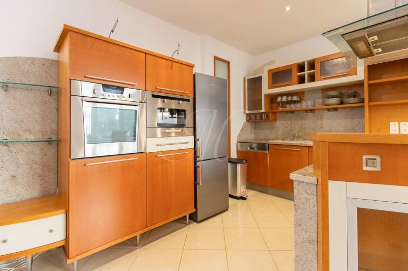 Küche in einer 4-Zimmer-Wohnung mit Edelstahlgeräten und Holzschränken.