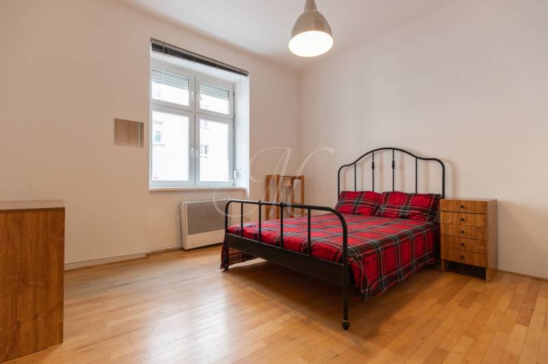 Schlafzimmer in einer 4-Zimmer-Wohnung mit Bett, Nachttischen und Boden mit Holzdekor.