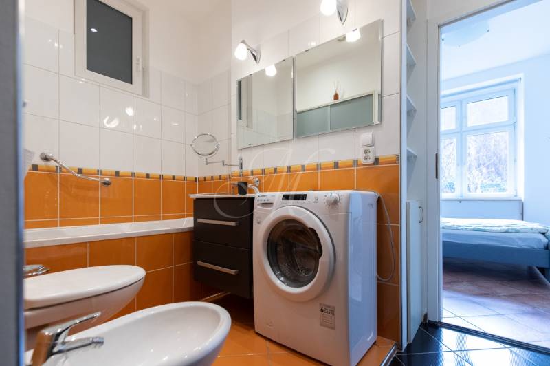 Badezimmer mit eingebauter Waschmaschine und orangefarbenen Fliesen in einer 4-Zimmer-Wohnung.