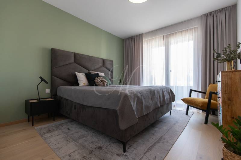 Schlafzimmer in einer 2-Zimmer-Wohnung mit großem Bett und grüner Wand.