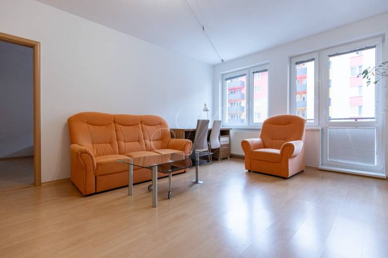 Wohnzimmer mit orangefarbenem Sofa und Holzboden in einer Zweizimmerwohnung.