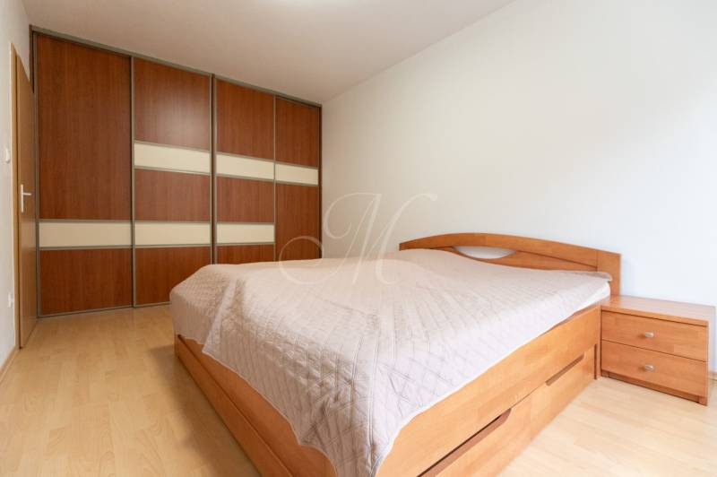 Schlafzimmer mit Holzboden und Einbauschrank in einer Zweizimmerwohnung.