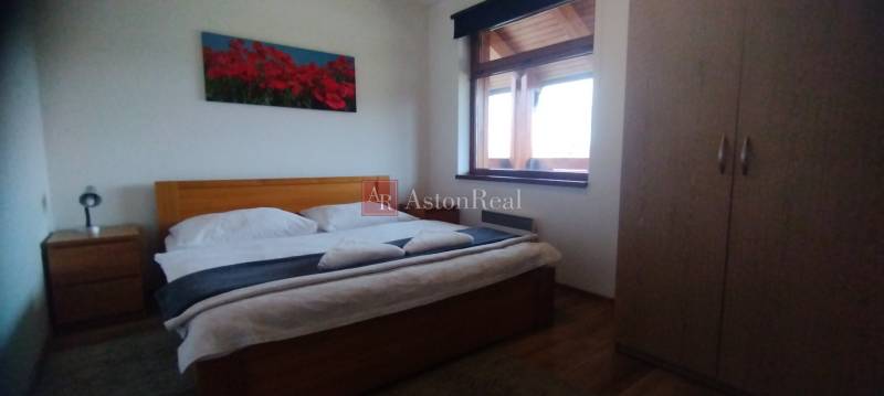 Schlafzimmer mit Doppelbett, Blumenbild und Schrank in einer 2-Zimmer-Wohnung.