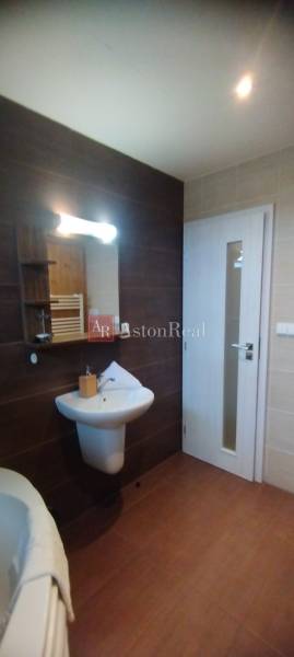 Badezimmer in einer 2-Zimmer-Wohnung mit Waschbecken, Spiegel und hellen Fliesen.