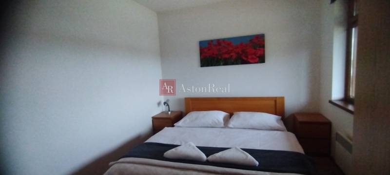 Schlafzimmer mit Doppelbett und Nachttischen aus Holz in einer Zweizimmerwohnung.