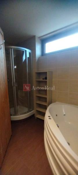 Badezimmer mit Dusche, Eckbadewanne und Boden mit Holzdekor in einer 2-Zimmer-Wohnung.