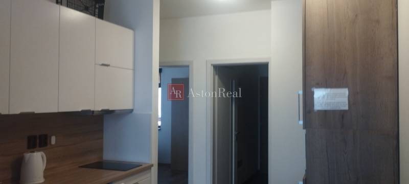 Küche mit weißen Schränken und Holzdekor in einer 2-Zimmer-Wohnung.