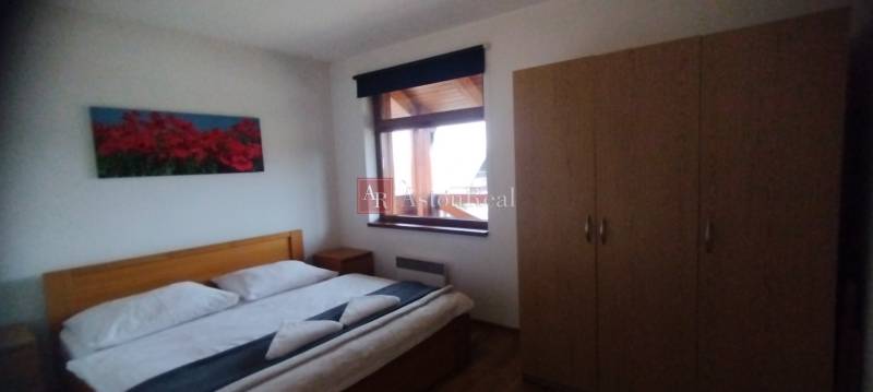 Schlafzimmer mit Doppelbett, Holzboden und Kleiderschrank in einer 2-Zimmer-Wohnung.