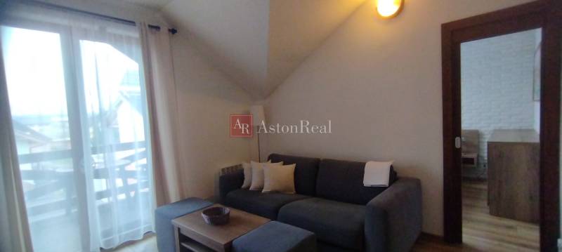 Wohnzimmer in einer Zweizimmerwohnung mit Sofa, Couchtisch und verglasten Balkontüren.