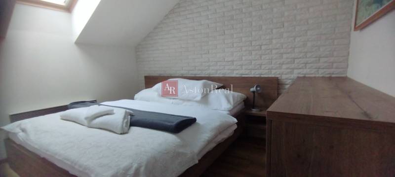 Schlafzimmer in einer 2-Zimmer-Wohnung mit Bett, Lampe und Ziegelverkleidung an der Wand.