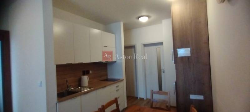 Küche in einer 2-Zimmer-Wohnung mit Holzboden und weißen Schränken.