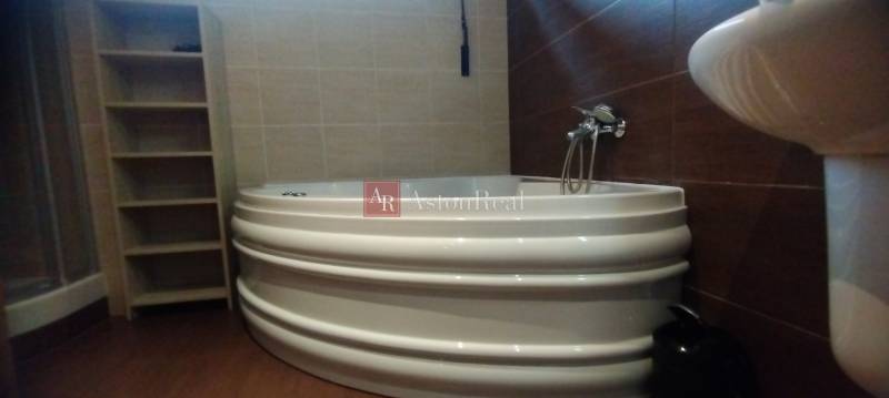 Badezimmer mit Eckbadewanne, Dusche und Regalschrank in einer 2-Zimmer-Wohnung.