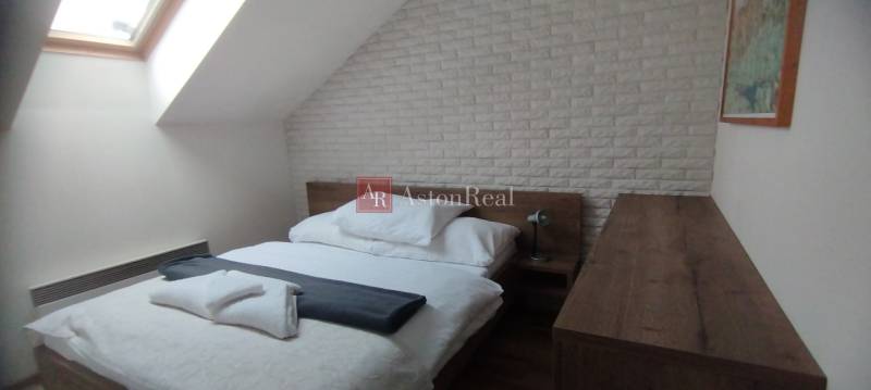 Schlafzimmer mit Bett und Dachfenster in einer 2-Zimmer-Wohnung mit dekorativem Ziegelverkleidung.