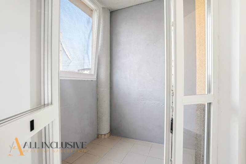 Verklebte Balkonwand in einer 2-Zimmer-Wohnung mit einfachen Fliesen und grauen Wänden.