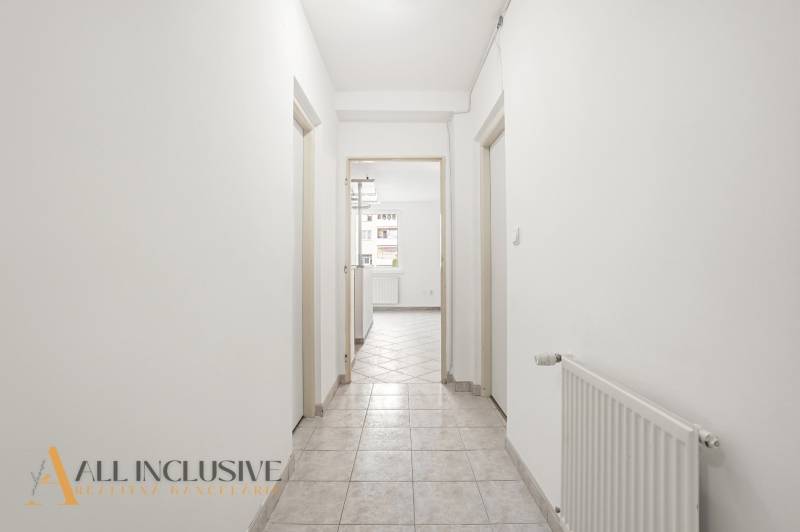 Flur in einer 2-Zimmer-Wohnung mit weißen Wänden und Fliesen.