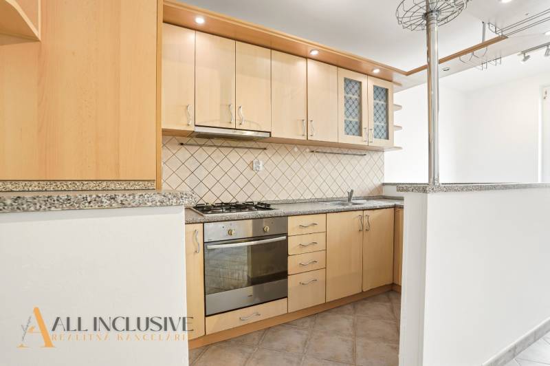 Küche in einer 2-Zimmer-Wohnung mit Holzschränken und einer Arbeitsplatte aus Stein.