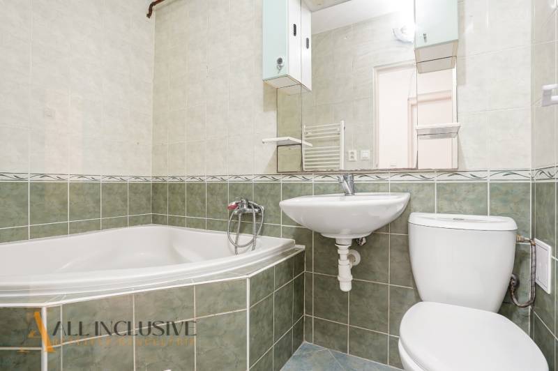 Badezimmer in einer 2-Zimmer-Wohnung mit Badewanne, Waschbecken und Toilette, gefliest mit grünen Fliesen.