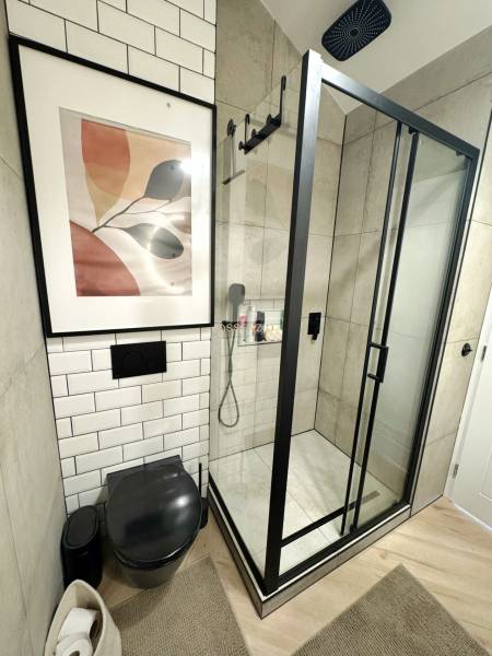 Badezimmer in einer 3-Zimmer-Wohnung mit verglaster Duschkabine und schwarzem WC.