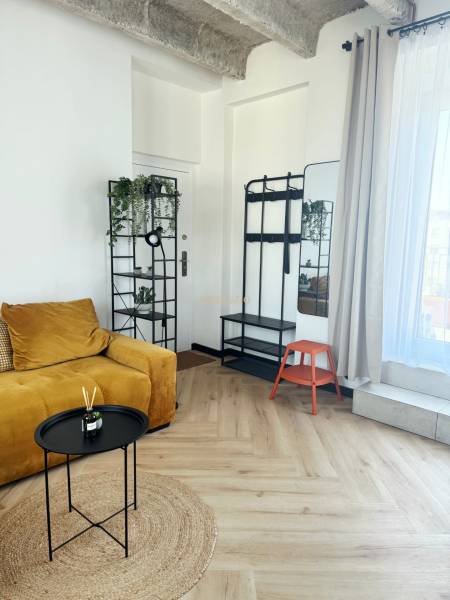 In der 3-Zimmer-Wohnung befinden sich ein senffarbenes Sofa, ein Ständer, ein Spiegel und ein Boden mit Holzdekor.