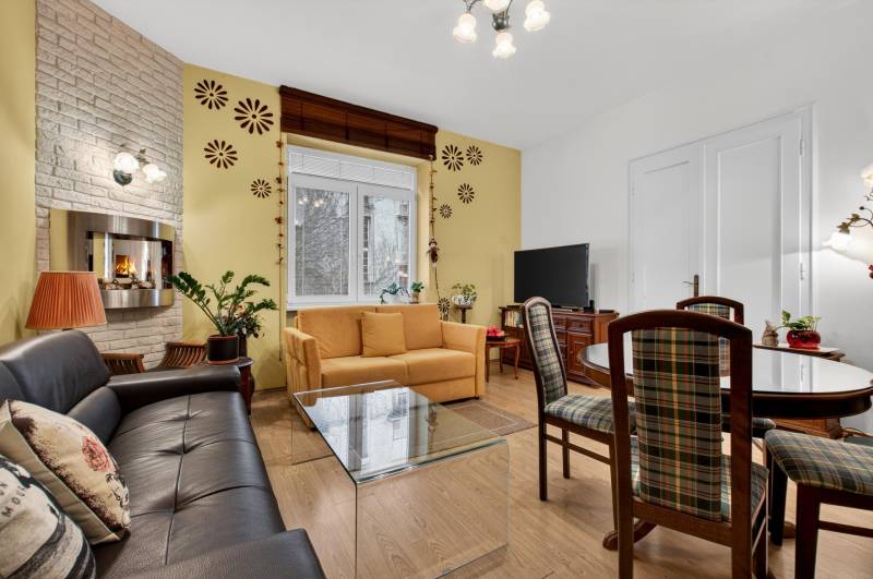 Helles Wohnzimmer mit Kamin, Sofa, Fernseher und Holzboden in einer 3-Zimmer-Wohnung.